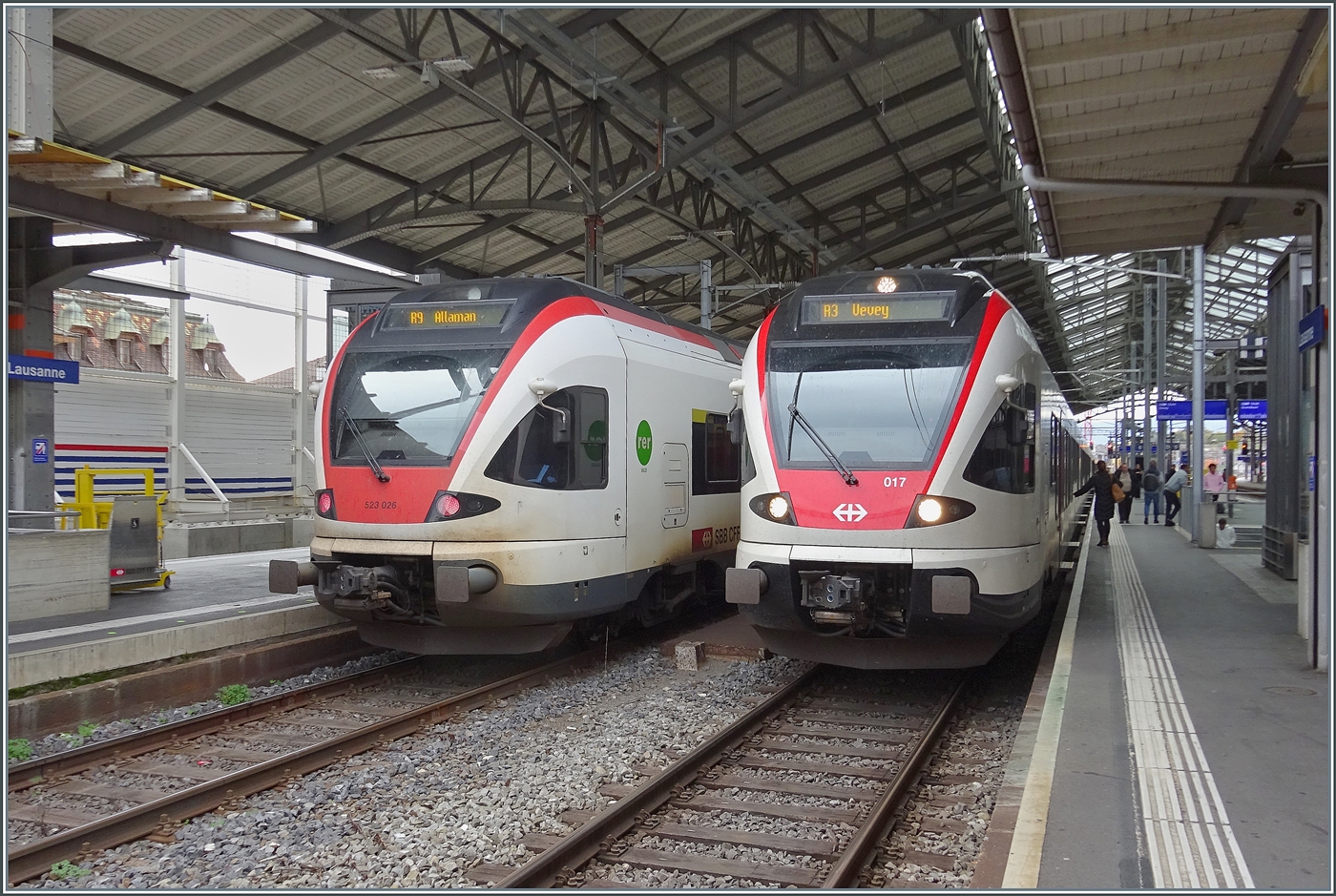 In Lausanne stehen zwei SBB Flirts RABe 523 und zeigen kleine, interessante Unterschiede: W�hrend der SBB RABe 523 026 sich in der traditionellen Farbgebung zeigt, ziert den SBB RABe 523 017 eine neuen Lackierung, welche durch das SBB Zeichen und die Nummer auf der Front auff�llt. 

29. Okt. 2026