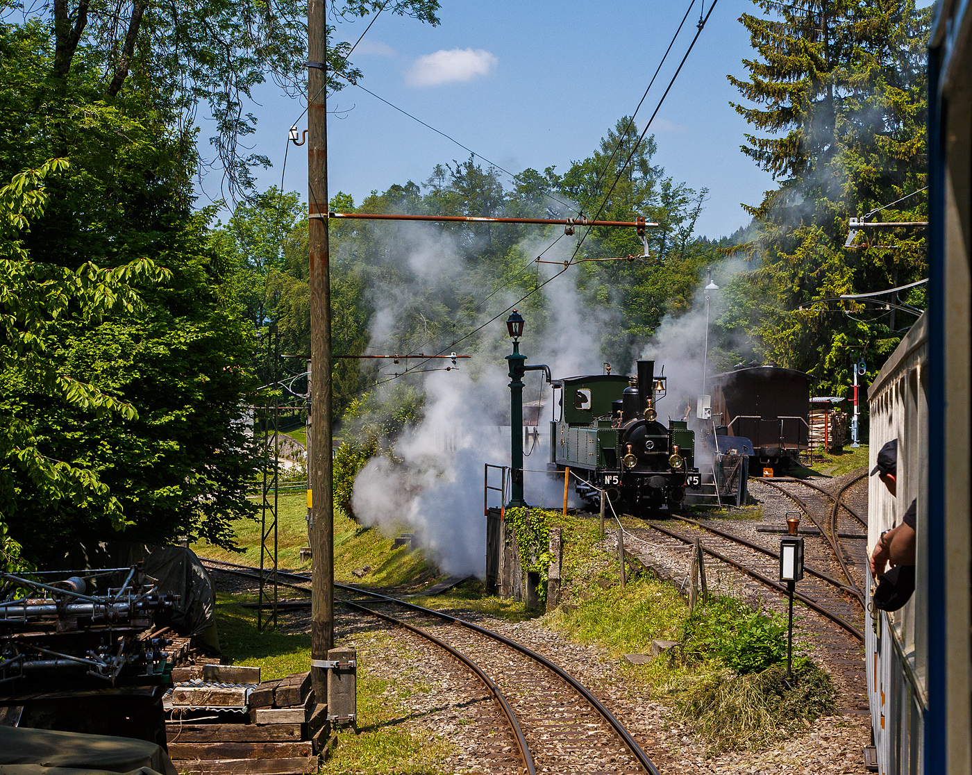 Museumsbahn-Romantik pur – Pfingsten 2023 (Samstag 27. bis Montag 29. Mai 2023) fand bei der Museumsbahn Blonay–Chamby das Schweizer Dampffestival 2023 / Festival suisse de la Vapeur 2023 statt.

Bei der Dampflok-Wartungsstelle der Museumsbahn Blonay–Chamby beim Museumsareal in Chaulin steht am 27.05. 2023 die G 3/3 LEB N° 5  Bercher  der Museumsbahn zum Kohlefassen. Links die Strecke 115 der MVR hinab nach Blonay, wir fahren mit dem ex MOB BCFe 4/4 11 rechts das Stichgleis zum Museum bzw. Depot hinauf.

Die ex LEB Nr. 5  Bercher  (Lausanne–Echallens–Bercher-Bahn) wurde 1890 von der Elsässische Maschinenbau-Gesellschaft Grafenstaden (später Société Alsacienne de Constructions Mécaniques) unter der Fabriknummer 4172 gebaut und an die Lausanne–Echallens–Bercher-Bahn geliefert. Die EMBG hatte auch zwei Jahre zuvor die baugleiche Nr. 2 geliefert. Die beiden dreiachsigen Tenderlokomotiven trugen die Hauptlast des Verkehrs, bis in den Jahren 1903 und 1905 zwei baugleichen Tenderlokomotiven, die G 3/3 6 „Gros-de-Vaud“ und G 3/3 7 „Talent „durch die Schweizerische Lokomotiv- und Maschinenfabrik (SLM) in Winterthur abgeliefert wurden. 

Von der YSteC konnte die LEB 1920/1921 die drei 1893 ebenfalls durch die EMBG gebauten Mallet-Lokomotiven G 2x2/2 Nr. 1 bis 3 gebraucht übernehmen. Nun waren die G 3/3 Nr. 2 und 5 nicht mehr gefragt. Während die G 3/3 2 „Échallens“ bereits 1929 verschrottet wurde (seit 1920 war sie bereits abgestellt), die G 3/3 Nr. 5  Bercher  hatte es da etwas besser, sie wurde 1934 an die Firma Energie de l’Ouest Suisse (EOS) für die Baustelle der Staumauer Grande-Dixence verkauf. Nach dem die Arbeiten 1935 erledigt sind geht sie bei der EOS außer Betrieb. Im Jahr 1939 verlässt die Schweiz und geht nach Vorarlberg in Österreich, zu einer Baufirma. Die Baufirma verschenkte 1967 die Lok und sie wurde, wie viele andere Dampflokomotiven zu dieser Zeit, auf einem Kinderspielplatz in der Stadt Feldkirch aufgestellt. Das Ausstellungsobjekt weckte die Aufmerksamkeit einiger Mitarbeiter der Museumsbahn Blonay–Chamby (BC), denen es gelang 1973 diese Lokomotive im Tausch gegen eine andere Lok zu erwerben.

Nach einer Aufarbeitung war die Lokomotive 1985 bis 2005 in Betrieb. Dann musste sie abgestellt werden. 2013/2014 wurde die Lokomotive ein zweites Mal durch die Museumseisenbahner aufgearbeitet. Seit dem Frühling 2015 ist die zweitälteste Schmalspur-Dampflokomotive der Schweiz, die älteste ist die G 3/4 1 „Rhätia  der Rhätischen Bahn (RhB), nach dem Abschluss der Revisionsarbeiten wieder in Betrieb.

TECHNISCHE DATEN der LEB G 3/3 N° 5  Bercher :
Baujahr: 1890
Spurweite: 1.000 mm
Achsformel: C
Länge über Puffer: 6.830 mm
Achsabstand: 1.800 mm (950mm / 850 mm)
Dienstgewicht: 20,4 t
Anzahl der Zylinder: 2
Zylindergröße: Ø 270 mm x 370 mm Kolbenhub
Treibraddurchmesser: 810 mm
Höchstgeschwindigkeit: 25 km/h
Stundenleistung: 150 PS
Kesselüberdruck: 12 bar
Kohlevorrat: 0,8 t
Wasservorrat: 2,2 m³

Die Lausanne–Echallens–Bercher-Bahn, abgekürzt LEB, französisch Chemin de fer Lausanne–Echallens–Bercher, ist eine meterspurige Privatbahn. Die knapp 24 Kilometer lange Strecke führt vom Stadtzentrum von Lausanne (Flon) durch die nördlichen Vororte und weiter nach Echallens und Bercher im Gros de Vaud, dem Waadtländer Hinterland. Die LEB ist eine moderne Vorortbahn, die in Lausanne teilweise unterirdisch verkehrt. Die Züge fahren alle 30 Minuten (zwischen Echallens und Bercher gibt es einige wenige Taktlücken am Vormittag). Werktags wird ein Viertelstundentakt bis Cheseaux angeboten. Von Montag bis Freitag verkehren in Lastrichtung einige beschleunigte Hauptverkehrszüge.