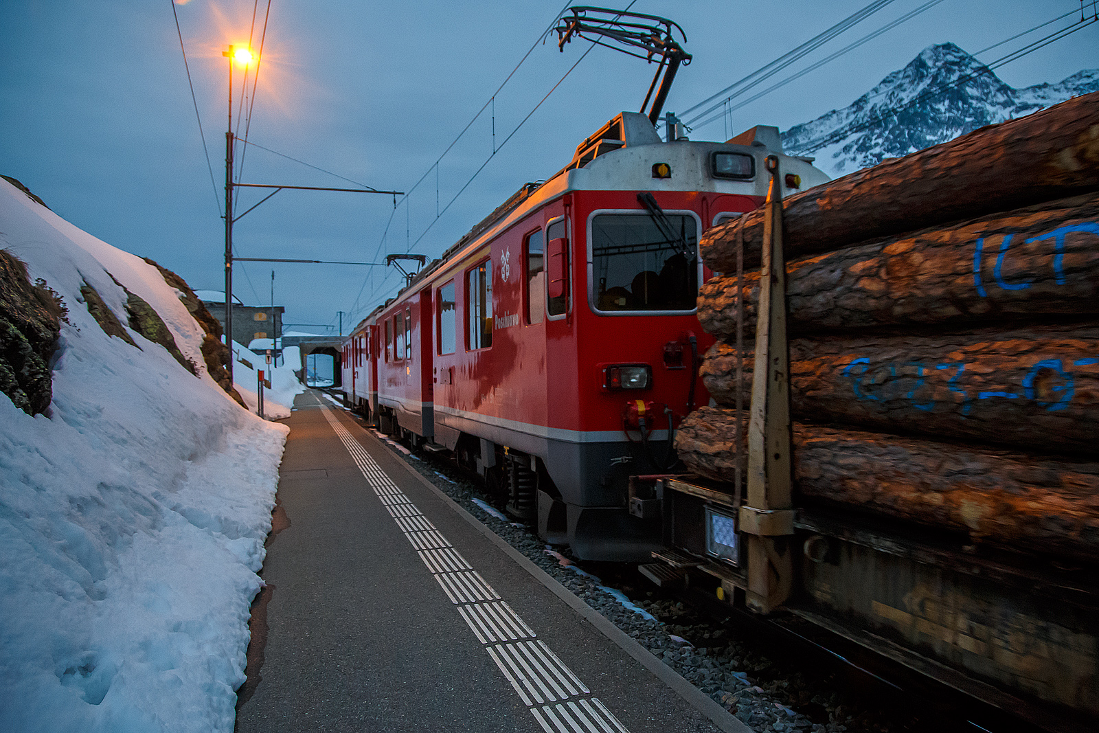 Nun haben die beiden RhB ABe 4/4 III Triebwagen 54  Hakone  und  51  Poschiavo  am 21.03.2023 als PmG (Personenzug mit Gterbefrderung) nach Poschiavo, fahren nun vom hchsten Punkt der Berninabahn, den Bahnhof Ospizio Bernina weiter nach Poschiavo.

Ab hier sind nun eher die Bremsen gefordert, denn nun geht es bis nach Poschiavo fast nur bergab. Von Pontresina nach Ospizio Bernina geht es nur bergauf, und wir merkten wie die Triebwagen arbeiten mussten.