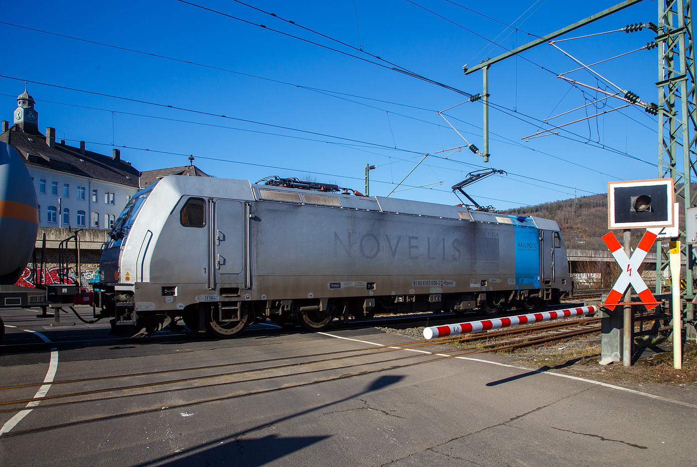 Nun sind die Schranken am Bü 343 geschlossen und sie hat Hp 1 oder 2...
Die 185 696-2 „Marie-Chanthou“ (91 80 6185 696-2 D-Rpool) der Railpool fährt am 14.02.2023 mit einem Druckgas-Kesselwagenzug über die Siegstrecke (KBS 460), durch Niederschelderhütte in Richtung Siegen.

Die TRAXX F140 AC2 wurde 2010 von Bombardier in Kassel unter der Fabriknummer 34722 gebaut und an die Railpool geliefert. Die Lok ist für Deutschland und Österreich zugelassen. Die ehemaligen Zulassungen für Schweden und Norwegen sind nun durchgestrichen.