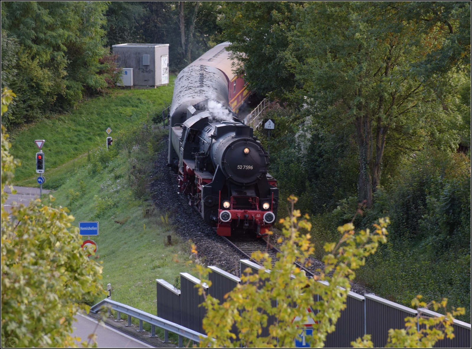 Schienenverkehr am Schienerberg. 

52 7596 mit ihrem EFZ-Sonderzug für die SEHR&RS hat gerade die Rheinbrücke von Hemishofen überquert und erreicht gleich den dortigen Bahnhof. Oktober 2022.