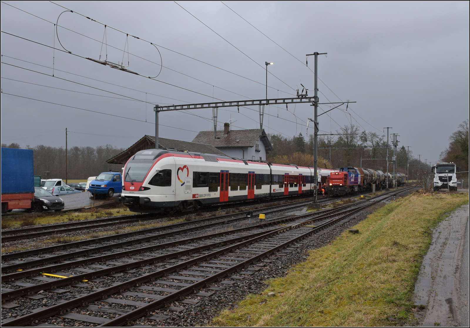 Schlechtwetter und ein Baustellendrama bei Frick. 

Am 843 093 wartet mit einigen Kesselwagen in Sisseln zwei Gegenzüge ab. Nachdem eine rote Am 843 mit einigen Bauwagen und einer Am 841 gekreuzt war, die ich nicht mehr erwischt habe, mussten noch die beiden Flirts RAB e523 011 und RABe 521 014 (im Bild) abgewartet werden. Februar 2026.