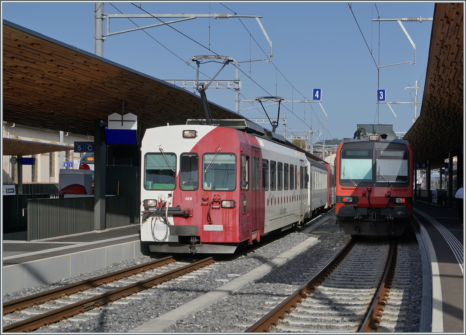 Schmal- und Normalspur in Bulle: Der TPF BDe 4/4 122 verlsst Bulle in Richtung Gruyre whrend der im Bahnsteigschatten stehende SBB Domino Ddingen als Ziel hat.

24. August 2023