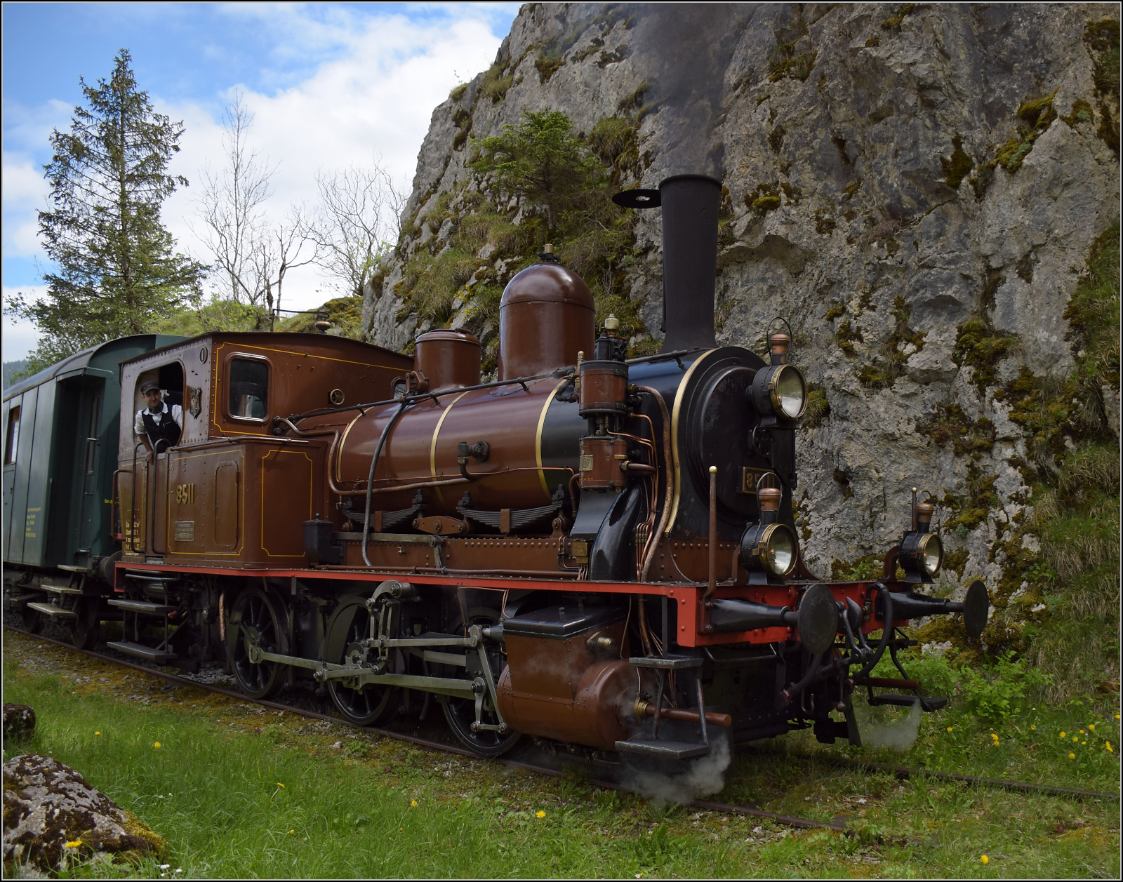 Train au fil de l'Areuse.

E 3/3 5811 fährt um die scharfe Kurve in den engen Canyon nach St-Sulpice. Fleurier, Mai 2024.