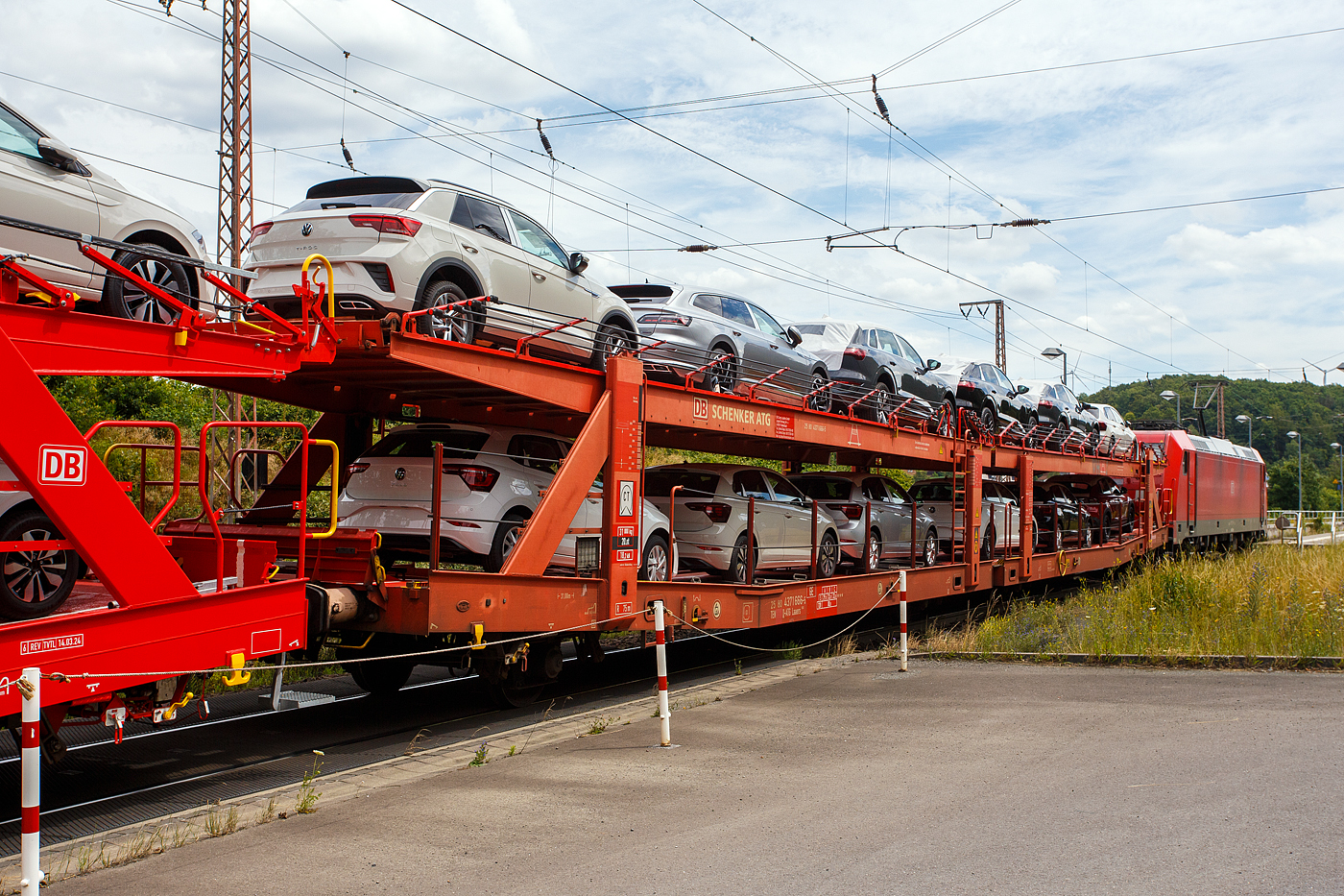 Vierachsiger (2 x zweiachsiger) Doppelstock-Autotransportwagen, 25 80 4371 666-5  D-ATG, der Gattung Laaers 560, der DB Cargo Logistics GmbH (ex DB Schenker ATG), am 19 Juli  2024 im Zugverband, direkt hinter der DB Cargo 185 230-0 (91 80 6185 230-0 D-DB), bei der Zugdurchfahrt in Rudersdorf (Kreis Siegen), hier beladen mit VW PKW´s aus der „Stadt des KdF-Wagens bei Fallersleben“ (ab 1945 Wolfsburg).

Diese Waggons haben zwei Ladeebenen und sind für den europaweiten Transport geeignet. Sie werden für den internationalen Transport von PKWs, SUVs und Vans eingesetzt und bieten maximale Flexibilität durch eine stufenlos verstellbare obere Ladeebene. Aufgrund der hohen Lastgrenze (bis 33 t) ist der Transport von besonders schweren Fahrzeugen der genannten Typen möglich.

Damit sowohl ein typenreiner Transport als auch eine Mischverladung in den unterschiedlichen Lademaßen möglich ist, kann die obere Ladeebene hinsichtlich der Transportstellungen stufenlos eingestellt werden.

Durch die Entwicklung eines veränderten Ladungssicherungssystems wurde den Kundenanforderungen nach optimierten Transportmöglichkeiten für Fahrzeuge mit niedrigerer Bodenfreiheit Rechnung getragen.

TECHNISCHE DATEN:
Gattung: Laaers (Bauart 560)
Erstes Baujahr der Wagengattung: 2007
Spurweite: 1.435 mm
Anzahl der Achsen: 4 (2 x 2)
Länge über Puffer : 31.000 mm
Achsabstände: 10.000 mm / 5.160 mm / 10.000 mm
Laufraddurchmesser (neu): äußere 840 mm und mittlere 730 mm
Ladelänge : 30.070 mm (unten) / 30.550 mm (oben)
Ladelänge waagerechter Teil untere Ebene: 19.400 mm
Ladebreite : 2.950 (unten) / 2.750 mm (oben)
Höchstgeschwindigkeit: 100 km/h (120 km/h leer)
Eigengewicht: 31.000 kg
Max. Zuladung bei Lastgrenze S: 33,0 t (ab Streckenklasse B, bei A 29,0 t)
Max. Zuladung der Ladeebenen: unten und oben jeweils max. 18 t
Max. Gewicht je Pkw: 2.800 kg (Radlast max. 1 t)
Anzahl der Radvorleger: 64
Höhe Geländer oben: 600 mm
Kleinster befahrb. Gleisbogenhalbmesser: 75 m
Bremse: KE-GP-A (K)
Bremssohle: Jurid 816 M
Handbremse: Ja
Intern. Verwendungsfähigkeit: TEN-GE
