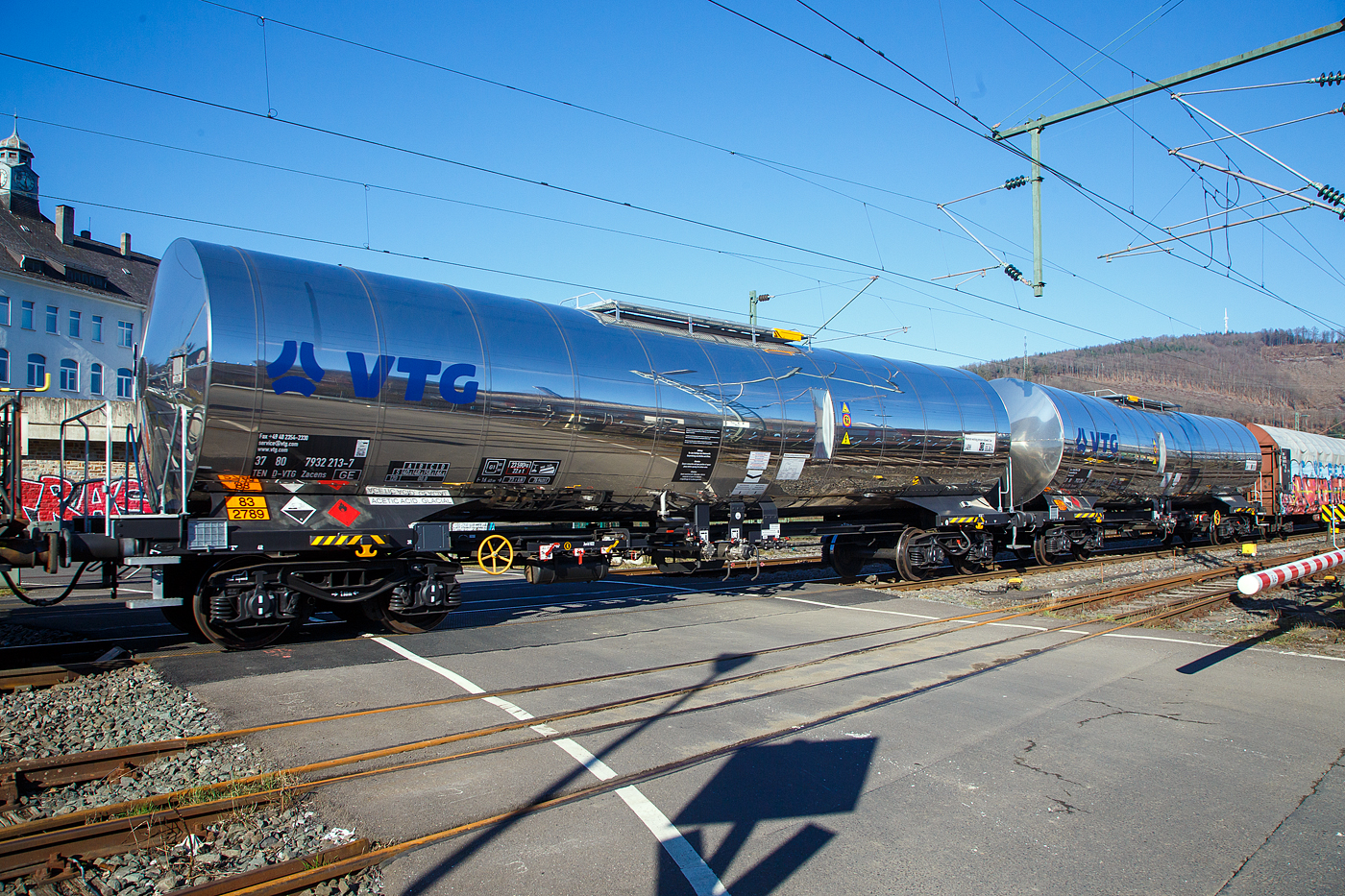 Vierachsiger 77 m³ Drehgestell-Kesselwagen mit Isolierung und Heizung, 37 80 7832 219-7 D-VTG der Gattung Zacens (VTG-Typ C52.077D), der VTG Rail Europe GmbH (Hamburg), im Zugverband am 14.02.2023 bei der Zugdurchfahrt in Niederschelden (Sieg). 
Die Gefahrguttafel (83/2789) zeigt es an: (oben) Gefahrgutnummer 83 = ätzender oder schwach ätzender Stoff, entzündbar (Flammpunkt von 23°C bis einschließlich 60°C) / (unten) UN-Nummer 2789 = ESSIGSÄURE mit mehr als 80 Masse-% Säure. Essigsäure ist eine farblose, flüssige, ätzende und typisch nach Essig riechende Carbonsäure. Als Lebensmittelzusatzstoff hat sie die Bezeichnung E260.

TECHNISCHE DATEN:
Gattung: Zacens
Spurweite: 1.435 mm
Länge über Puffer : 16.400 mm
Drehzapfenabstand: 11.360 mm
Achsabstand im Drehgestell: 1.800 mm
Höchstgeschwindigkeit: 100 km/h (120 km/h leer)
Kleinster befahrbarer Gleisbogen: R= 35 m
Eigengewicht: 23.290 kg
Nutzlast: 66,7 t (ab Streckenklasse D)
Gesamtvolumen: 76.940 Liter (ca. 77 m³)
Max. Betriebsdruck: 3 bar
Tankcode: L4BH
Behälterwerkstoff : Edelstahl
Heizung: 6-strängig, außen liegend, 8,4 m
Bauart der Bremse: KE – GP (K)
Bremssohle: Jurid 822
Handbremse: Ja, vom Boden bedienbar
Intern. Verwendungsfähigkeit: TEN-GE