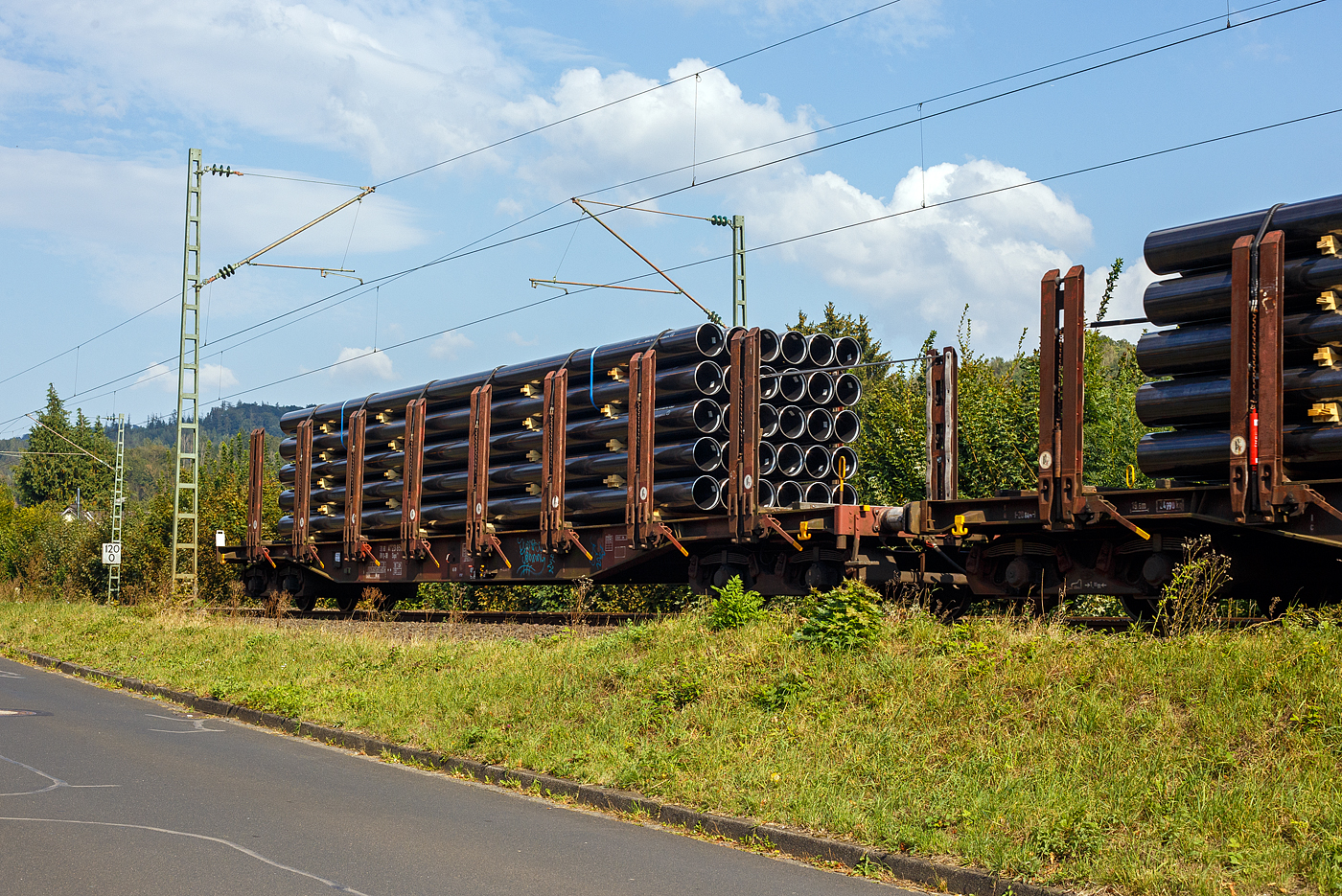 Vierachsiger Drehgestell-Flachwagen mit 8 Doppelrungenpaaren mit integrierter Niederbindeeinrichtung, 31 80 4723 857-7 D-DB, der Gattung Snps 719.1, der DB Cargo AG, am 19 September 2024 im Zugverband bei einer Zugdurchfahrt im Bahnhof Kirchen (Sieg). Hier beladen mit HFI-längsnahtgeschweißte Stahlrohre Ø 323.9 (DN/NW 300 mm bzw. 12 ¾ Inch) in Herstellungslänge vom 12 m. Der Hersteller der Stahlrohre ist die Salzgitter Mannesmann Line Pipe GmbH in Siegen (ex RW Fuchs).

Der Drehgestell-Flachwagen wurde speziell für den Transport von Rohren, Profilstahl, Flachstahlprodukten sowie Stamm- und Schnittholz entwickelt und zeichnet sich durch hohe Ladekapazität aus. Das Ladegut wird durch Rungen mit Schichtholzleisten und Kunststoffspitzen geschont (nur bei BA 719.1 Stahlhalbzeuge. Wird bei der BA 719.0 Timber (Holz) nicht benötigt und ist daher auch nicht montiert.). Die Längsseiten sind jeweils mit acht besonders breiten und belastbaren Rungen ausgerüstet, die mit dem Untergestell fest verbunden sind. Zur Verzurrung des Ladegutes ist jedes Rungenpaar mit einer Niederbindeeinrichtung versehen, die von einer Person bedient werden kann. Die Wagen wurden ab 1980 als Sps 719 beschafft und ab 1988 in Snps 719 umgezeichnet.

Zur Aufnahme und Abstützung der Ladung sind auf dem Wagenboden Ladeschwellen und an den Wagenlängsseiten Rungen angebracht. Zur Verzurrung der Ladung sind von Hand zu bedienende Niederbindeeinrichtungen vorhanden. Für die Auflage des Ladegutes sind hölzerne Ladeschwellen im Rungenbereich und im Abstand von 1 m von Wagenende vorhanden. Außerdem sind feste 5 mm niedrigere Hilfsladeschwellen zwischen den Rungen zur Unterstützung von leicht durchhängendem Ladegut (z. B. Schnittholz) angeordnet. Die Ladeschwellen sind genügend hoch, so dass die handelsüblichen Umschlagmittel verwendet werden können. Der Wagenboden ist mit einem begehbaren Loch- bzw. Riffelblech vollständig abgedeckt. Zur Aufnahme von Lasten oder zum Befahren mit Flurförderfahrzeugen sind die Abdeckungen nicht geeignet. Zur Sicherung der Ladung sind auf jeder Wagenlängsseite in gleichmäßigen Abständen 8 Rungen vorhanden. Die Rungen sind mit dem Untergestell-Außenlangträger fest verbunden und so ausgeführt, dass sie die durch die Ladung entstehenden Kräfte in Wagenlängs- und Wagenquerrichtung sicher aufnehmen können. Die Innenseiten der Rungen sind ausgekleidet.

Zur Verzurrung des Ladegutes ist jedes Rungenpaar mit einer Niederbindeeinrichtung ausgerüstet, die von einer Person bedient werden kann. Die Spanngurte sind zur Schonung des Ladegutes mit einem elastischen Werkstoff ummantelt. Die Länge des Gurtes und die Teilung der Raster sind so gewählt, dass auch Ladungen, die nur etwa die halbe Rungenhöhe einnehmen, verzurrt werden können.

TECHNISCHE DATEN:
Gattung: Snps 719.1
Spurweite: 1.435 mm (Normalspur)
Länge über Puffer: 20.840 mm
Drehzapfenabstand: 15.800 mm
Radsatzstand in den Drehgestellen: 1.800 mm
Ladelänge: 19.000 mm
Ladebreite: 2.723 mm (zwischen den Rungen)
Fußbodenhöhe über SO: 1.280 mm (OK Ladeschwelle)
Rungenhöhe: 2.000 mm
Eigengewicht: 24.400 kg
Zuladung bei Lastgrenze S: 63 t (ab Streckenklasse D)
Max. Geschwindigkeit: 100 km/h / 120 km/h (leer)
Kleinster Gleisbogenhalbmesser: 35 m
Bauart der Bremse: KE-GP (LL)
Bremssohle: IP 116
Handbremse: Ja
Verwendungsfähigkeit: RIV