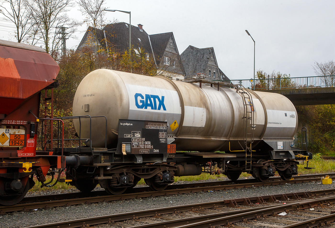 Vierachsiger-Drehgestell Kesselwagen für Salpetersäure (>97%) mit Bremserbühne, der Gattung Zacns, registriert als 33 80 7929 695-4 D-GATXD der GATX Rail Germany GmbH abgestellt, im Zugverband eines Übergabezuges der KSW, am 03.11.2022 in Herdorf auf dem Rbf. der KSW. Mieter des Wagens ist die SKW Stickstoffwerke Piesteritz GmbH (Wittenberg). 

Die Gefahrguttafel (885/2031) zeigt es auch noch an: (oben) Gefahrgutnummer 885 = stark ätzender Stoff / (unten) UN-Nummer 2031 = Salpetersäure, andere als rotrauchend, mit mehr als 70 % Säurebrandfördernd. Hier sogar (laut Anschrift) größer 97 %. Die reine Säure ist farblos und hat einen scharf stechenden Geruch. Sie wird unteranderem zur Herstellung von Sprengstoffen verwendet, was hier der Fall ist.

Der Wagen wurde 2003 vom rumänischen Wagonbauer Meva S.A. DrobetaTurnu – Severin gebaut,

TECHNISCHE DATEN:
Gattung: Zacns (Gattungszahl 7629)
Spurweite: 1.435 mm
Länge über Puffer : 12.860 mm
Drehzapfenabstand: 7.820 mm
Achsabstand im Drehgestell: 1.800 mm
Laufraddurchmesser 920 mm (neu)
Höchstgeschwindigkeit: 100 km/h
Eigengewicht: 20.250 kg
Nutzlast: 69,7 t ab Streckenklasse D3 (CM 63,7 t)
Kleinster befahrbarer Gleisbogen: R 35 m
Gesamtvolumen: 50,450 Liter
Prüfdruck: 4 bar
Zulässiger Betriebsüberdruck: 3 bar
Tankcode: L10DH
Behälterwerkstoff : Edelstahl
Intern. Verwendungsfähigkeit: RIV

Auch im dahinter befindlichen Wagen dem gedeckten Schüttgutwagen 21 80 0734 600-8 D-DB, der Gattung Tds 937, wurde ein Rohstoff für die Herstellung von Sprengstoffen transportiert und zwar Ammoniumnitrat.