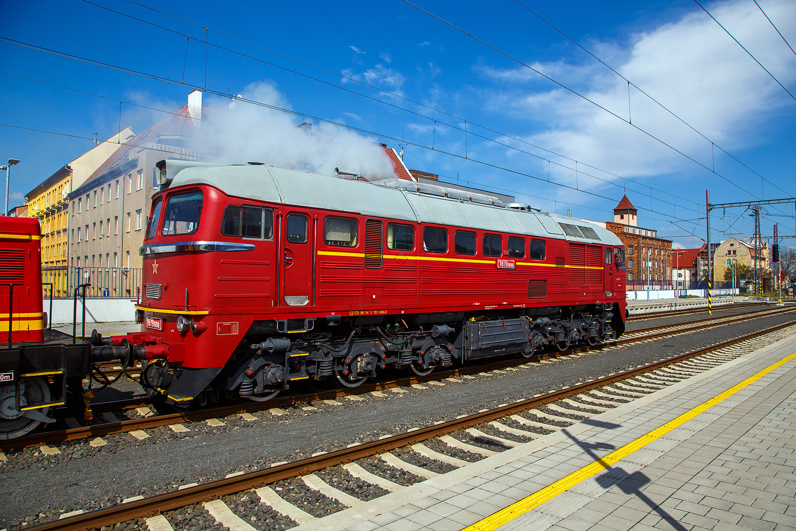 Wie in „alten Zeiten“ der ČSD in der Tschechoslowakei.....
Im Bahnhof Cheb (Eger) rangiert am 21.04.2023, die ex ČSD T679.1600 „Don Cicío“, heutige ČD 781 600-2 (CZ-ČD 90 54 3 781 600-2) mit dem Rotkäppchen („Karkulka“) T 444.030 (heute CZ- ČD 90 54 3 725 030-1) am Haken. Die Dieselabgaswolke kann man am Bild ja sehen, leider nicht den Sound.

Lokomotive der wurde 1979 von der Lokomotivfabrik Luhansk, deutsche Transliteration Luhanskyj Teplowosobudiwnyj Sawod (LTS), in der damaligenSowjetunion (heute Ukraine) unter der Fabriknummer 3426 gebaut. Die Herstellerbezeichnung ist LTS M62. Die für die DDR gebaute Variante (weitgehend baugleich mit dieser hier) der sowjetischen Bauart M62 sind in Deutschland bekannt als DR V 200 „Taigatrommel“, später DR 120, zuletzt DB 220.

Die ČSD-Baureihe T 679.1 (ab 1988 Baureihe 781) sind dieselelektrische Lokomotiven der ehemaligen Tschechoslowakischen Staatsbahn (ČSD) für den schweren Güterzugdienst. Wegen ihrer Herkunft erhielten die Lokomotiven den Beinamen Sergej. 

Die Lokomotiven wurden ab Mitte der 60er Jahre in der sowjetischen Lokomotivfabrik Woroschilowgrad (später Luhansk) für den Einsatz bei den Bahnverwaltungen des gesamten RGW entwickelt und produziert. Nachdem bereits die Ungarische Staatsbahn (MÁV) und die Polnischen Staatsbahnen (PKP) Lokomotiven dieses Typs beschafft hatten, entschied sich Mitte der 60er Jahre auch die ČSD für solche Lokomotiven.

1966 wurden die ersten 50 Lokomotiven an die ČSD geliefert. Bis 1979 beschaffte die ČSD insgesamt 599 Lokomotiven dieser Baureihe. 25 Lokomotiven der ersten Serie wurden breitspurig als T 679.5 für die grenzüberschreitende Strecke Bahnstrecke Uschhorod–Haniska (Sowjetunion, heute Ukraine) in Dienst gestellt. Nach der Elektrifizierung ihrer Stammstrecke in den Jahren 1973 bis 1978 wurden sie dort nicht mehr benötigt. Ein Teil dieser Lokomotiven wurde darum auf Regelspur umgespurt. Acht Lokomotiven blieben jedoch für die Bedienung der Werksanschlüsse breitspurig und erhielten ab 1988 die neue Baureihenbezeichnung 781.8. Die breitspurigen Lokomotiven wurden 1991 ausgemustert und verschrottet. 

Bereits 1987 verringerte sich der Lokomotivbestand erstmals, als neun Lokomotiven an die Ungarische Staatsbahn MÁV verkauft wurden. Nach 1990 wurden die Lokomotiven durch den zurückgehenden Güterverkehr und die fortschreitende Elektrifizierung der wichtigsten Hauptstrecken zunehmend überflüssig. 1997 endete der Einsatz der Sergejs in der Slowakei. In Tschechien waren die Lokomotiven für den schweren Güterverkehr auf der sogenannten „Podkrušnohorska magistrála“ (Strecke Chomutov–Cheb) vorerst unverzichtbar. Letztes Einsatzgebiet der Lokomotiven in Tschechien waren die schweren Kohleganzzüge von Sokolov zum Kraftwerk Arzberg in Oberfranken. Diese Verkehre endeten am 30. November 2002 mit der Stilllegung des Kraftwerkes.

Konstruktion und Technik:
Die M62 ist als schwere sechsachsige Güterzuglokomotive konstruiert. Der Rahmen ist als selbsttragender Brückenrahmen aus zwei inneren Hauptlängsträgern aus Doppel-T-Trägern und zwei äußeren Längsträgern aus U-Profilen aufgebaut, die durch Deckbleche und die Zugkästen an den Frontseiten verbunden sind. Der Lokkasten ist aus gekanteten Profilen und gesickten Blechen geschweißt. Der Rahmen der dreiachsigen Drehgestelle besteht aus zwei äußeren Längs- und zwei inneren Querträgern und dem darüber angeordneten Drehzapfenträger. Der hierauf mit dem Drehzapfenlager aufgesetzte Lokkasten ist mit einer Abstützrückstelleinrichtung abgestützt.

Herzstück dieser Lok ist der Dieselmotor, ein wassergekühlter V 12 Zylinder- Zweitakt- mit zwei Abgasturboladern und Rootsgebläse mit einem Hubraum von 149,6 Litern  vom Typ Kolomna 14 D 40. Die mechanische Leistung beträgt 1.470 kW (1.998 PS) bei einer Drehzahl von 750 U/min. Die Leistung wurde durch einen fremderregten Gleichstromgenerator für die Fahrmotoren in Gleichstrom umgewandelt. Die Leistungsregelung erfolgte durch einen magnetischen Flussregler im Erregerfeld der Erregermaschine. Die Fahrmotoren sind Reihenschlussmotoren. Deren Traktionsleistung betrug zusammen 1,270 kW (1727 PS). Um Ankerströme und Drehmoment der Fahrmotoren im oberen Geschwindigkeitsbereich wieder anzuheben, besaß die Lok zwei Shuntierungsstufen, die parallel zu den Erregerwicklungen der sechs Tatzlager-Fahrmotoren geschaltet wurden. Eine ähnliche Konstruktion verwendet die Lokfamilie der DR-Baureihe 130. Entsprechend der Auslegung als Güterzuglokomotive besitzt die M62 keine Zugheizeinrichtung. Einsätze im Reisezugdienst waren daher auf wärmere Jahreszeiten beschränkt oder erforderten den Einsatz von Heizwagen bzw. von Wagen mit Eigenheizung.

Ein besonderes Bauteil ist das Rootsgebläse, es fördert Verbrennungsluft und erzeugt eine Vorverdichtung von 0,2 bar. Das ist notwendig, weil ein Zweitakt-Motor durchgespült werden muss, er kann mit gleichzeitig offenen Einlassschlitzen und Auslassventilen nicht selbsttätig ansaugen. Nach dem Start laufen die beiden Turbolader hoch und steigern den Ladeluftdruck auf rund 1,2 bar. Der Dieselmotor hat eine Leerlaufdrehzahl von 400 U/min, aber schon bei 750 U/min seine Höchstdrehzahl. Der Motor besitzt Zylinder in V-Anordnung mit je 12,46 Litern Hubraum. Dabei sitzen die Kolben der B-Seite mit Anlenkpleueln auf den Hauptpleueln der A-Seite. Damit ändern sich die Kolbengeschwindigkeiten zwischen A- und B-Seite. Der Motor erzeugt auf beiden Zylinderbänken unterschiedlich viel Leistung. Der Kraftstoffvorrat beträgt 3.900 Liter Dieselöl.

Die Lüfter für Fahrmotoren und Traktionsgenerator sind mechanisch über Gelenkwellen vom Dieselmotor angetrieben. Der Kühlerlüfter wurde auch direkt vom Dieselmotor angetrieben, zur Steuerung ist eine Strömungskupplung dazwischengeschaltet.

Charakteristisches Merkmal der ersten Lieferserien der M62, die noch ohne Schalldämpfer geliefert wurde, war das laute Auspuffgeräusch, das ihnen in der DDR zum Spitznamen „Taigatrommel“ verhalf.  In Deutschland, Tschechien und der Slowakei sind die M62 aus dem Dienst der Staatsbahnen ausgeschieden, in allen anderen Ländern sind sie noch im Einsatz. 

TECHNISCHE DATEN:
Gebaute Anzahl: 574  Stück T 679.1 und 25 Stück T 679.5 (Breitspur)
Hersteller:  Lokomotivfabrik Lugansk
Baujahre: 1966 bis 1979
Achsformel: Co’Co’
Spurweite:  1.435 mm (1.520 mm bei T 679.5)
Länge über Puffer: 17.550 mm
Höhe: 4.493 mm
Breite: 2.950 mm
Drehzapfenabstand: 8.600 mm
Achsabstand im Drehgestell: 4.200 mm (2 x 2.100 mm)
Treibraddurchmesser:  1.050 mm
Kleinster bef. Halbmesser: 125 m
Dienstgewicht: 116 t 
Höchstgeschwindigkeit: 100 km/h
Installierte Leistung: 1.471 kW (1.998 PS)
Traktionsleistung (Leistung am Rad): 1.271 kW (1.727 PS)
Anfahrzugkraft: 260 kN
Dauerzugkraft: 200 kN
Motorentyp: Kolomna 14 D 40
Motorbauart: Zweitakt-Zwölfzylinder-V-Motor
Nenndrehzahl: 750 U/min (Leerlauf 400 U/min)
Leistungsübertragung: elektrisch
Anzahl der Fahrmotoren: 6 vom Typ ED 107
Tankinhalt: 3.900 l
Bremse: ŠKODA N-O, Dako-BS-2

Quellen: Wikipedia, atlaslokomotiv.net