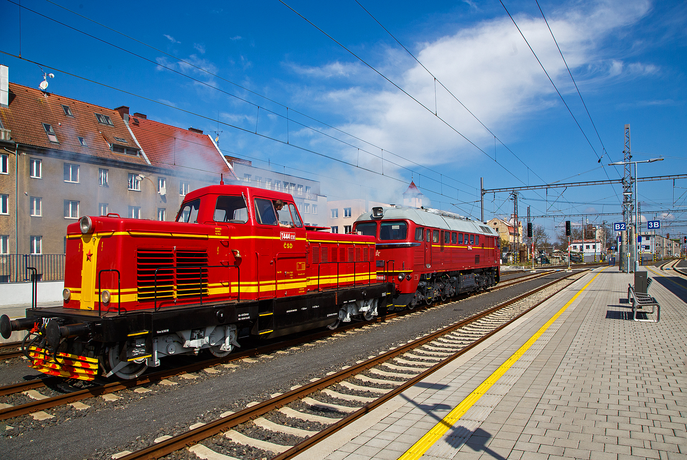 Wie in „alten Zeiten“ der ČSD in der Tschechoslowakei.....
Im Bahnhof Cheb (Eger) rangiert am 21.04.2023, die ex ČSD T679.1600 „Don Cico“, heutige ČD 781 600-2 (CZ-ČD 90 54 3 781 600-2) mit dem Rotkppchen („Karkulka“) T 444.030 (heute CZ- ČD 90 54 3 725 030-1) am Haken. Die Dieselabgaswolke kann man am Bild ja sehen, leider nicht den Sound.

Die T 444.030 „Karkulka“ (Rotkppchen): 
Das Rotkppchen („Karkulka“) T 444.030 (heute CZ- ČD 90 54 3 725 030-1) wurde 1963 von der Lokfabrik Turčianska strojarne n. p. Martin unter der Fabriknummer  40-00028 gebaut.

Die Baureihe T 444.0 (ab 1988 Baureihe 725) ist/war eine der wenigen dieselhydraulischen Lokomotiven der Tschechoslowakischen Staatsbahn ČSD. Sie wurde entwickelt, um auf Nebenbahnen und im Rangierdienst den Dampfbetrieb zu ersetzen. Die ersten zwei Prototypen wurden 1959 von ČKD in Prag geliefert. Die Serienfertigung erfolgte bei Turčianske strojarne n. p. Martin in der heutigen Slowakei. Insgesamt wurden fr die ČSD 113 und fr Industriebetriebe 61 Maschinen gebaut und ausgeliefert.

Die wegen des roten Anstriches „Karkulka“ (Rotkppchen) genannten Lokomotiven besaen einen Reduktionswandler fr den Strecken- und Rangierdienst. Aus Ihnen wurden die sptere Baureihe T 444.1 mit einem Dampfkessel fr die Wagenheizung abgeleitet. Dadurch wurde die Brennstoffreserve bei der BR T 444.1 von 4000 l auf 1500 l verkleinert. Die T 444.0 wurden 1988 in die Baureihe 725 umgezeichnet. Da die Lokomotiven keinen Dampfkessel besaen und der Gterverkehr auf Nebenbahnen kontinuierlich zurckging, konnte bis 1992 auf ihre Dienste verzichtet werden. Etliche Maschinen sind jedoch fahrfhig erhalten geblieben

TECHNISCHE DATEN:
Gebaute Anzahl: 174
Hersteller: ČKD (Entwicklung und Prototypen), Turčianska strojarne n. p. Martin
Baujahre:  1959–1965
Spurweite: 1.435 mm
Achsformel: B´ B´ 
Lnge ber Puffer: 12.640 mm
Dienstgewicht: 56 t
Treibraddurchmesser:  1.000 mm
Motor: V-12-Zylinder-Viertakt-Dieselmotor vom Typ ČKD K 12 V 170 DR
Motorleistung: 534 kW (726 PS), Nenndrehzahl 1400 U/min
Hchstgeschwindigkeit: 70 km/h Streckengang / 35 km/h Rangiergang
Anfahrzugkraft: 158 kN
Leistungsbertragung: hydrodynamisch


Die T679.1600 „Don Cico“, heutige ČD 781 600-2 :
Der „Sergej“, die heutige ČD 781 600-2  wurde 1979 von der Lokomotivfabrik Luhansk, deutsche Transliteration Luhanskyj Teplowosobudiwnyj Sawod (LTS), in der damaligen Sowjetunion (heute Ukraine) unter der Fabriknummer 3426 gebaut. Die Herstellerbezeichnung ist LTS M62. Die fr die DDR gebaute Variante (weitgehend baugleich mit dieser hier) der sowjetischen Bauart M62 sind in Deutschland bekannt als DR V 200 „Taigatrommel“, spter DR 120, zuletzt DB 220.

Die ČSD-Baureihe T 679.1 (ab 1988 Baureihe 781) sind dieselelektrische Lokomotiven der ehemaligen Tschechoslowakischen Staatsbahn (ČSD) fr den schweren Gterzugdienst. Wegen ihrer Herkunft erhielten die Lokomotiven den Beinamen Sergej. 

Die Lokomotiven wurden ab Mitte der 60er Jahre in der sowjetischen Lokomotivfabrik Woroschilowgrad (spter Luhansk) fr den Einsatz bei den Bahnverwaltungen des gesamten RGW entwickelt und produziert. Nachdem bereits die Ungarische Staatsbahn (MV) und die Polnischen Staatsbahnen (PKP) Lokomotiven dieses Typs beschafft hatten, entschied sich Mitte der 60er Jahre auch die ČSD fr solche Lokomotiven.

1966 wurden die ersten 50 Lokomotiven an die ČSD geliefert. Bis 1979 beschaffte die ČSD insgesamt 599 Lokomotiven dieser Baureihe. 25 Lokomotiven der ersten Serie wurden breitspurig als T 679.5 fr die grenzberschreitende Strecke Bahnstrecke Uschhorod–Haniska (Sowjetunion, heute Ukraine) in Dienst gestellt. Nach der Elektrifizierung ihrer Stammstrecke in den Jahren 1973 bis 1978 wurden sie dort nicht mehr bentigt. Ein Teil dieser Lokomotiven wurde darum auf Regelspur umgespurt. Acht Lokomotiven blieben jedoch fr die Bedienung der Werksanschlsse breitspurig und erhielten ab 1988 die neue Baureihenbezeichnung 781.8. Die breitspurigen Lokomotiven wurden 1991 ausgemustert und verschrottet. 

Bereits 1987 verringerte sich der Lokomotivbestand erstmals, als neun Lokomotiven an die Ungarische Staatsbahn MV verkauft wurden. Nach 1990 wurden die Lokomotiven durch den zurckgehenden Gterverkehr und die fortschreitende Elektrifizierung der wichtigsten Hauptstrecken zunehmend berflssig. 1997 endete der Einsatz der Sergejs in der Slowakei. In Tschechien waren die Lokomotiven fr den schweren Gterverkehr auf der sogenannten „Podkrunohorska magistrla“ (Strecke Chomutov–Cheb) vorerst unverzichtbar. Letztes Einsatzgebiet der Lokomotiven in Tschechien waren die schweren Kohleganzzge von Sokolov zum Kraftwerk Arzberg in Oberfranken. Diese Verkehre endeten am 30. November 2002 mit der Stilllegung des Kraftwerkes.

Konstruktion und Technik:
Die M62 ist als schwere sechsachsige Gterzuglokomotive konstruiert. Der Rahmen ist als selbsttragender Brckenrahmen aus zwei inneren Hauptlngstrgern aus Doppel-T-Trgern und zwei ueren Lngstrgern aus U-Profilen aufgebaut, die durch Deckbleche und die Zugksten an den Frontseiten verbunden sind. Der Lokkasten ist aus gekanteten Profilen und gesickten Blechen geschweit. Der Rahmen der dreiachsigen Drehgestelle besteht aus zwei ueren Lngs- und zwei inneren Quertrgern und dem darber angeordneten Drehzapfentrger. Der hierauf mit dem Drehzapfenlager aufgesetzte Lokkasten ist mit einer Absttzrckstelleinrichtung abgesttzt.

Herzstck dieser Lok ist der Dieselmotor, ein wassergekhlter V 12 Zylinder- Zweitakt- mit zwei Abgasturboladern und Rootsgeblse mit einem Hubraum von 149,6 Litern  vom Typ Kolomna 14 D 40. Die mechanische Leistung betrgt 1.470 kW (1.998 PS) bei einer Drehzahl von 750 U/min. Die Leistung wurde durch einen fremderregten Gleichstromgenerator fr die Fahrmotoren in Gleichstrom umgewandelt. Die Leistungsregelung erfolgte durch einen magnetischen Flussregler im Erregerfeld der Erregermaschine. Die Fahrmotoren sind Reihenschlussmotoren. Deren Traktionsleistung betrug zusammen 1,270 kW (1727 PS). Um Ankerstrme und Drehmoment der Fahrmotoren im oberen Geschwindigkeitsbereich wieder anzuheben, besa die Lok zwei Shuntierungsstufen, die parallel zu den Erregerwicklungen der sechs Tatzlager-Fahrmotoren geschaltet wurden. Eine hnliche Konstruktion verwendet die Lokfamilie der DR-Baureihe 130. Entsprechend der Auslegung als Gterzuglokomotive besitzt die M62 keine Zugheizeinrichtung. Einstze im Reisezugdienst waren daher auf wrmere Jahreszeiten beschrnkt oder erforderten den Einsatz von Heizwagen bzw. von Wagen mit Eigenheizung.

Ein besonderes Bauteil ist das Rootsgeblse, es frdert Verbrennungsluft und erzeugt eine Vorverdichtung von 0,2 bar. Das ist notwendig, weil ein Zweitakt-Motor durchgesplt werden muss, er kann mit gleichzeitig offenen Einlassschlitzen und Auslassventilen nicht selbstttig ansaugen. Nach dem Start laufen die beiden Turbolader hoch und steigern den Ladeluftdruck auf rund 1,2 bar. Der Dieselmotor hat eine Leerlaufdrehzahl von 400 U/min, aber schon bei 750 U/min seine Hchstdrehzahl. Der Motor besitzt Zylinder in V-Anordnung mit je 12,46 Litern Hubraum. Dabei sitzen die Kolben der B-Seite mit Anlenkpleueln auf den Hauptpleueln der A-Seite. Damit ndern sich die Kolbengeschwindigkeiten zwischen A- und B-Seite. Der Motor erzeugt auf beiden Zylinderbnken unterschiedlich viel Leistung. Der Kraftstoffvorrat betrgt 3.900 Liter Diesell.

Die Lfter fr Fahrmotoren und Traktionsgenerator sind mechanisch ber Gelenkwellen vom Dieselmotor angetrieben. Der Khlerlfter wurde auch direkt vom Dieselmotor angetrieben, zur Steuerung ist eine Strmungskupplung dazwischengeschaltet.

Charakteristisches Merkmal der ersten Lieferserien der M62, die noch ohne Schalldmpfer geliefert wurde, war das laute Auspuffgerusch, das ihnen in der DDR zum Spitznamen „Taigatrommel“ verhalf.  In Deutschland, Tschechien und der Slowakei sind die M62 aus dem Dienst der Staatsbahnen ausgeschieden, in allen anderen Lndern sind sie noch im Einsatz. 

TECHNISCHE DATEN:
Gebaute Anzahl: 574  Stck T 679.1 und 25 Stck T 679.5 (Breitspur)
Hersteller:  Lokomotivfabrik Lugansk (LTS)
Baujahre: 1966 bis 1979
Achsformel: Co’Co’
Spurweite:  1.435 mm (1.520 mm bei T 679.5)
Lnge ber Puffer: 17.550 mm
Hhe: 4.493 mm
Breite: 2.950 mm
Drehzapfenabstand: 8.600 mm
Achsabstand im Drehgestell: 4.200 mm (2 x 2.100 mm)
Treibraddurchmesser:  1.050 mm
Kleinster bef. Halbmesser: 125 m
Dienstgewicht: 116 t 
Hchstgeschwindigkeit: 100 km/h
Installierte Leistung: 1.471 kW (1.998 PS)
Traktionsleistung (Leistung am Rad): 1.271 kW (1.727 PS)
Anfahrzugkraft: 260 kN
Dauerzugkraft: 200 kN
Motorentyp: Kolomna 14 D 40
Motorbauart: Zweitakt-Zwlfzylinder-V-Motor
Nenndrehzahl: 750 U/min (Leerlauf 400 U/min)
Leistungsbertragung: elektrisch
Anzahl der Fahrmotoren: 6 vom Typ ED 107
Tankinhalt: 3.900 l
Bremse: KODA N-O, Dako-BS-2

Quellen: Wikipedia, atlaslokomotiv.net
