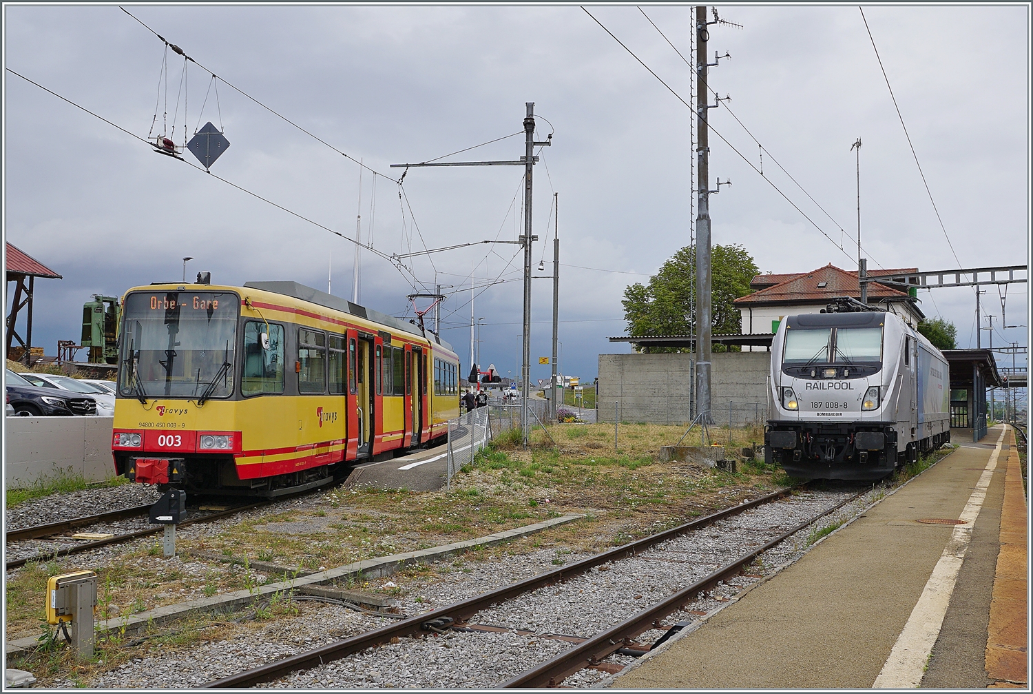 Zwei in Deutschland imatrikulierte Fahrzeuge stehen in Chavonray: Links wartet der TRAVYS/OC Be 4/8 003 auf die Abfahrt nach Orbe und rechts die an die BLS vermietete RailPool 187 008-8 auf ihre Güterlast. 

15. August 2022