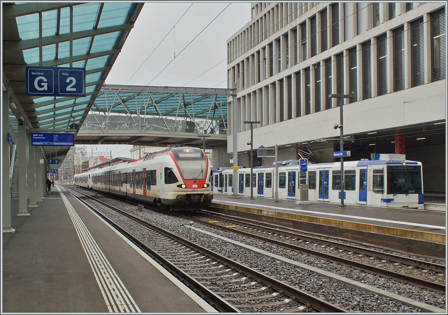 Zwei SBB Flirt verlassen Renens VD nach Vallorbe und Le Brassus (Flügelzug). Im Hintergrund ist ein TL TSOL Be 4/6 als m1 zu sehen. 

14. Dez. 2023