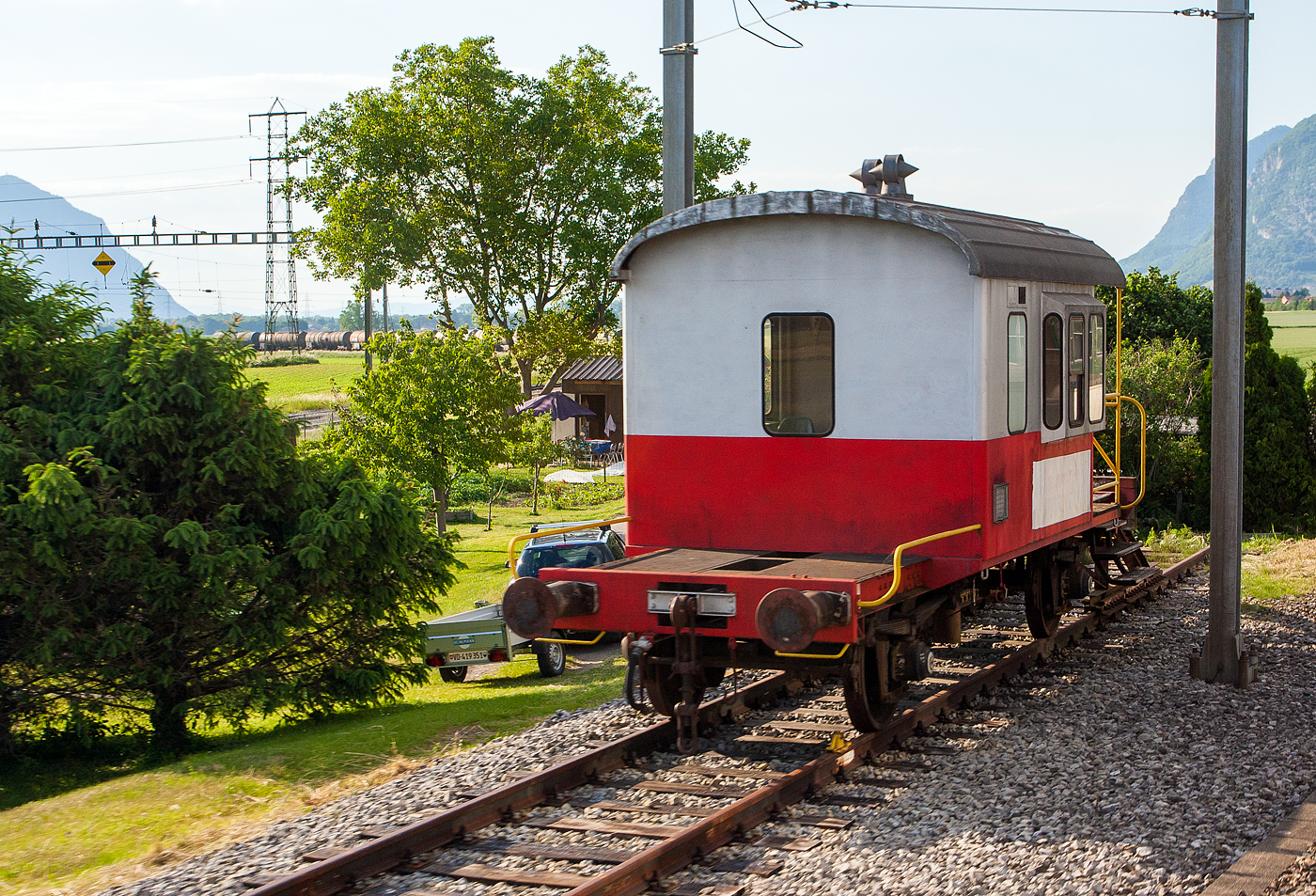 Zweiachsiger Gterzugbegleitwagen „Sputnik“ abgestellt auf einem Abstellgleis am 28 Mai 2012 in Saint-Triphon (VD), aufgenommen aus einem Zug heraus.

Diese Wagen wurden ursprnglich als Dienstbegleitwagen Db 60 85 99-29 xxx-x bezeichnet, wegen der Beobachtungsfunktion am Zugschluss von Gterzgen wurde sie von den Eisenbahnern „Sputnik“ genannt. Ende der 1980er wurden sie zum Dienstwagen (Browagen) Xs 40 85 95 35 xxx-x um bezeichnet. Die SBB Wagen waren ursprnglich im damaligen SBB-Grn lackiert. Der Wagen hier ist in der  Swiss-Express  Lackierung, er wurde ggf. zuletzt als Kuppelwagen fr die berfhrung einzelner EW III mit Mittelpufferkupplung eingesetzt. Da sich hier keine Beschriftungen (sind bermalt) an dem Wagen befinden, kann ich nicht sagen ob es sich um einen SBB oder BLS Wagen handelt.

Ab 1957 bauten die SBB im Werk Chur in mehreren Serien auf Untergestellen abgebrochener Personenwagen insgesamt 385 Stck dieses zweiachsigen Dienstbegleitwagens der Gattung Db. In Anspielung auf die Beobachtungsfunktion wurden die Wagen von den Eisenbahnern als „Sputnik“ genannt. Die BLS baute fr den eigenen Bedarf ebenfalls sechs Sputniks. Wegen des kurzen Achsstandes von nur 5 Metern bei einer Lnge von 9,24 m und des geringen Gewichtes von 10 t wurde das Zugpersonal bei schneller Fahrt (max. 100 km/h) im Aufenthaltsraum und am Beobachtungsposten regelrecht durchgeschttelt. 

Ausgestattet war der Wagen mit Einrichtungsgegenstnden ausrangierter Personenwagen. So fand man in dem auf ein Wagengestell aufgesetzten Huschen eine WC-Kabine ohne Splung, aber mit einem Wasserkbel, eine doppelte Holzbank aus der dritten Klasse und einen Gasofen mit Ofenrohr. Die Gasflaschen befanden sich auf einer der Plattformen in einem Kasten, welcher dem Zugpersonal auch als Sitz an der frischen Luft dienen konnte. Der Wagen lief grundstzlich am Zugschluss. Mit dem Abbau der Begleitung von Gterzgen wurde der Bestand reduziert und Anfang der 1990er Jahre endete der Einsatz. Sputnik-Wagen wurden auch fr andere Zwecke adaptiert, beispielsweise als Kuppelwagen fr die berfhrung einzelner EW III mit Mittelpufferkupplung.

TECHNISCHE DATEN:
Spurweite: 1.435 mm (Normalspur)
Anzahl der Achsen: 2
Lnge ber Puffer: 9.240 mm
Drehzapfenabstand: 5.000 mm
Eigengewicht: ca. 10.000 kg
Nutzlast: 0 t 
Hchstschwindigkeit: 100 km/h
Bauart der Bremse: Dr-P (10 t)