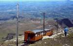 Ein Zug der Chemin de Fer de La Rhune, von den Einheimischen als  Petit Train  bezeichnet, hat im April 1986 die Bergstation in 910 m Höhe erreicht. Über dem Zug ist weiter unten ein Teil der Zahnradstrecke erkennbar.