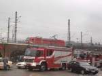 2 rote Fahrzeuge - BR 185 mit einem Gterzug und ein FeuerwehrFahrzeug beim Einsatz am Hallenser Hauptbahnhof am Morgen des 19.11.14