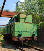 Etwas für Fotos ungünstig stehend, die Verschub-Dampflokomotive Emil Mayrisch 5, eine Krupp Bergbau, am 05 Juni 2011 im LWL-Industriemuseum Henrichshütte in Hattingen (bis 2007 WIM - Westfälisches Industriemuseum).

Die Krupp Typ Bergbau wurde 1953 Lokomotiv- und Waggonbaufabrik Krupp (LOWA) der Friedrich Krupp AG in Essen unter der Fabriknummer 3077 gebaut und als Lok IX an die Gewerkschaft Auguste-Victoria in Marl-Sinsen. Bis zu seiner Schließung 2015 war das Bergwerk das drittletzte aktive Steinkohlebergwerk Deutschlands sowie das zweitletzte im Ruhrgebiet.

1968 ging die Lok aber an die Grube Anna in Alsdorf des EBV - Eschweiler Bergwerks-Verein AG und wurde 1983 als ANNA Nr. 7 geführt, von 1983 bis zur Ausmusterung 1992 wurde die Lok  Emil Mayrisch 5  geführt. Im Jahr 1993 ging sie an das Bergbaumuseum Wurmrevier e. V. in Alsdorf und ging aber ende der 1990er an das damalige als geführt WIM - Westfälisches Industriemuseum, Standort Henrichshütte in Hattingen. 

Beschreibung des Typs  Bergbau  der Lokomotivfabrik Krupp (Essen):
Die normalspurige, vierachsige Tenderlokomotive war Teil des Nachkriegs-Typenprogramm Lokomotivfabrik in Essen und wurde sowohl in einer Naßdampf- als auch in einer Heißdampfversion geliefert. Zwischen 1948 und 1962 entstanden 30 Lokomotiven dieses Typs in der Lokomotivfabrik Krupp AG. Die  Bergbau  war nicht nur die leistungsstärkste, sondern mit Abstand mit 80 t die schwerste Maschine unter den Nachkriegsbauarten. 

Entstehungsgeschichte:
Während des Zweiten Weltkrieges erhielt Krupp den Auftrag zur Entwicklung einer schweren Dh2t-Lokomotivbauart für die Reichswerke Hermann Göring in Salzgitter, nach 1945 ging diese endgültig in der Salzgitter AG auf, die sich bis Ende der 1980er Jahre im Besitz der Bundesrepublik Deutschland befand. Nach Abschluss der Konstruktionsarbeiten wurde der Bau der 13 bestellten Maschinen kriegsbedingt zur Firma Werkspoor in Utrecht verlagert. Die Niederlande war ja von den deutschen Truppen besetzten worden. Bis zum Kriegsende konnte allerdings keine Lok fertig gestellt werden. Die angearbeiteten Baugruppen wurden kurz vor dem Abzug der Besatzungstruppen noch nach Essen überführt, wo sie nach Komplettierung und Endmontage ab 1948 zur ersten Serie der Bergbau wurden. 

Bauart:
Die Krupp Bergbau war für den schweren Übergabe- und Verschubdienst von Industrie- und Werksbahnen konzipiert. Entsprechend diesem Einsatzzweck war sie besonders robust und kräftig ausgeführt. Dank ihres vergleichsweise hohen Kesseldrucks, der großen Zylinder und des günstigen Übersetzungsverhältnisses war die mit vollen Vorräten 80 t schwere und rund 1.000 PSi starke Lok nicht nur die leistungsfähigste Type des Krupp-Industrielokprogramms, sondern die schwerste und stärkste vierachsige deutsche Tenderlok überhaupt. Im unteren Geschwindigkeitsbereich übertraf ihre Zugkraft sogar die der sechsachsigen Schlepptenderlok der Baureihe 50. Die zulässige Höchstgeschwindigkeit betrug 50 km/h. Zwecks Erzielung günstiger Kurvenlaufeigenschaften lagen nur der erste und dritte Radsatz fest im Rahmen, der zweite und vierte Radsatz waren jeweils um 15 mm seitenverschiebbar.

Die Type wurden in mehreren Baulosen gefertigt, die sich teilweise äußerlich unterscheiden lassen; die ersten beiden Serien besaßen viereckige Führerhausstirnfenster nach Art der Kriegslokomotiven, kantige Führerhausdächer und zwei sichtbare Kesselaufbauten (Dampfdom mit zwei Sandkästen unter gemeinsamer Verkleidung, separater Speisedom); später gebaute Loks hatten ovale Stirnfenster, abgerundete Führerhausdächer sowie eine durchgehende Verkleidung von Speisedom, Dampfdom und nur noch einem Sandkasten. Da sich der Wasservorrat von zunächst 8 m³ bei den auf der Hafenbahn der HOAG (Walsum – Oberhausen) eingesetzten Loks als etwas knapp erwiesen hatte, wurde ein Teil der später gebauten Maschinen mit vergrößerten hinteren Vorratsbehältern ausgerüstet. Der hintere Überhang wuchs dadurch um 150 mm, der Wasservorrat nahm auf 10 m³ zu. Einige Maschinen wurden ab Werk mit einem Mischvorwärmer ausgerüstet.

TECHNISCHE DATEN:
Gebaute Anzahl: 30
Baujahre: 1948 bis 1962
Bauart: D n2t oder D h2t
Spurweite: 1.435 mm (Normalspur)
Länge über Puffer: 11.100–11.250 mm (je nach Bauserie)
Höhe: 4.150 mm
Breite: 3.130 mm
Gesamtachsstand: 4.500 mm (3 x 1.500 mm)
Treibraddurchmesser: 1.200 mm (neu)
Dienstgewicht: 80 t
Höchstgeschwindigkeit: 50 km/h (vorwärts / rückwärts), diese zuletzt 25 km/h
Indizierte Leistung: 735 kW / 1.000 PS
Anfahrzugkraft: 223 kN
Kesselüberdruck: 15 bar
Zylinder: 2 (Ø 630 mm x 600 mm Hub)
Steuerungsart: Heusinger auβen
Rostfläche: 2,46 m² 
Überhitzerfläche: 42 m² 
Verdampfungsheizfläche: 118 m²
Wasservorrat: 10,0 m³
Kohlevorrat: 3 t
Kleinster bef. Halbmesser: 100 m
Bremse: Knorr 
