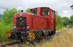 
Die O+K Lok V3  NAHMER  der Sauerländer Kleinbahn (MME Märkische Museums-Eisenbahn), ex V3 der Hohenlimburger Kleinbahn AG (HKB) ist am 18.08.2013 am Gleisende beim Bahnhof Hüinghausen zur Gleissicherung abgestellt.

Die Firma Orenstein und Koppel (O&K), Werk Dortmund-Dorstfeld lieferte 1960 insgesamt 5 baugleiche, zweiachsige dieselhydraulische Lokomotiven (1.000 mm Spurweite) des Typs MV8 mit Endführerstand, an die Hohenlimburger Kleinbahn AG. Die Lokomotiven waren mit einer pneumatischen Mehrfachsteuerung ausgerüstet, da die Züge ins Nahmertal größtenteils mit 2 Maschinen gefahren werden mussten. Die Kraftübertragung auf die Räder erfolgt über Blindwelle und Kuppelstangen. Bis zur Betriebseinstellung der HKB am 23.12.1983 waren die Maschinen im Einsatz. Am 28.07.1984 gelangte die Lok Nr.3 in den Besitz der Märkischen Museumseisenbahn (MME). Dort erhielt sie in Erinnerung an ihre alte Heimat den Namen  NAHMER , nach dem gleichnamigen Bach in dessen Tal die Bahn verlief. 

Technische Daten: 
Fabriknummer: 25988 
Spurweite: 1.000 mm 
Länge über Puffer: 5.900 mm 
Achsabstand: 1.500 mm 
Dienstgewicht: 20.700 kg 
Motor: Orenstein & Koppel wassergekühlter 6 Zylinder 4-takt Dieselmotor 116 V6 D 
Hubraum: 10,85l 
Motorleistung: 140 PS (103 kW) bei 1.500 U/min 
Getriebe: Voith L22 nV Zweigang-Turbogetriebe (Wandler+Kupplung) 
Höchstgeschwindigkeit: 17,5 km/h