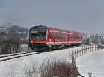 Der 628 576 als RB nach Mhldorf am 16.02.2010 bei der Ausfahrt aus Pfarrkirchen mit der Gartlbergkirche und der Stadtpfarrkirche im Hintergrund.