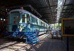 Der kombinierte Speise- und Gepäckwagen vom Typ Plan D – NS RD 7659 am 29 April 2025 im Het Spoorwegmuseum (bis 2005 NSM - Nederlands Spoorwegmuseum / Niederländischen Eisenbahnmuseum) in Utrecht im ehemaligen Bahnhof Maliebaan.
Der Halbgepäck-/Halbspeisewagen wurde 1951 von Beijnes, offiziell Koninklijke Fabriek van Rijtuigen en Spoorwagens J.J. Beijnes (Königliche Fabrik für Kutschen und Eisenbahnwagen J.J. Beijnes) in Haarlem gebaut und an die NS (Niederländische Eisenbahn) geliefert. Dieser Wagen wurde als RD 7659 und später ab 1966 als 51 84 87-40 111-0 geführt.
Der kombinierte Speise- und Gepäckwagen war 1951 eine Neuheit bei der NS. Die Wagentypen (Gattung) wurden kombiniert, da sowohl die einzelnen Speisewagen als auch die Gepäckwagen über erhebliche Kapazitätsüberschüsse verfügten. Aus betrieblicher Sicht war eine Kombination wirtschaftlicher. Die Serie dieser Plan D Wagen der Gattung WRD bestand aus 10 Stück (RD 7651-7660). Die NS setzte den kombinierten Wagen auch im internationalen Verkehr ein. 
An Bord befanden sich eine Bar und eine Kombüse. Die Kombüse enthielt einen Kohleofen, einen Kühlschrank, eine Spüle und Stauraum. Der Speiseraum bot Platz für 15 Passagiere. Der Wagen verfügte außerdem über ein Schaffnerabteil, eine Telefonzelle (Telefon war nie installiert) und einen Informationspoint (wo ebenfalls nie einer saß). 1954 wurde der Speiseraum auf 23 Sitzplätze erweitert. Dies ging auf Kosten der Bar und des Informationabteils. Die Telefonzelle blieb als leerer, abgeschlossener Raum bestehen. Im anderen Teil des Wagens befand sich ein großes, abschließbares Gepäckabteil. Der Waggon wurde speziell für die Ausstellung 'Tosti’s, Truffels en Treinen' im Juni 2020 wunderschön restauriert und erhielt dank von Spenden der BankGiro Lottery, der Stichting Goede Doelen Nh1816 (Nh1816 Charity Foundation) und des Vereins der Freunde des Eisenbahnmuseums seine ursprüngliche türkise Farbe zurück.
Die Plan D Wagen:
Plan D ist die Typenbezeichnung für eine Reihe von Reisezugwagen (D-Zug-Wagen) die zwischen 1950 und 1951 von den beiden Herstellern Werkspoor oder Beijnes gebaut wurden. Diese Wagen waren von 1950 bis 1987 bei den Niederländischen Eisenbahnen (NS) im Einsatz. 
Die NS beschloss 1949, ihren stark dezimierten Fuhrpark um siebzig D-Zugwagen zu ergänzen, die die Typenbezeichnung Plan D erhielten. Die Bestellung an Werkspoor und Beijnes umfasste zwanzig Wagen der ersten und zweiten Klasse (AB), vierzig Wagen der dritten Klasse (C) und zehn Wagen mit Speise- und Gepäckabteilen (RD), somit insgesamt 70 Wagen. 
Die Wagenkastenkonstruktion entsprach weitgehend den der Rundkopfwagen die zwischen 1935-1939 gebaut worden waren. Die Böden, die zuvor aus Holz bestanden, bestanden nun aus geripptem Blech mit Korkfüllung. Durch die Verwendung dieses gerippten Materials konnten verschiedene Querkonstruktionen entfallen. Auch die Drehgestelle waren anders konstruiert und orientierten sich an der Vorkriegsbauart „IT“, heute Bauart „S“.
Das Erscheinungsbild der Wagen veränderte sich durch zusätzliche Dachrinnen und elektrische Schlusslichter. Die zuvor verwendeten Schlusslichteisen blieben aufgrund ihres internationalen Einsatzes erhalten. Die Wagen hatten zudem ein Abteil weniger als die alten Rundkopfwagen.
Die Wagen wurden ab 1950 in der damals neuen türkisfarbenen Lackierung in Betrieb genommen. Gezogen von den ebenfalls neuen und in gleicher Farbe gelieferten Elektrolokomotiven der Baureihen 1100, 1200 und 1300 wurden sie für Schnellzüge eingesetzt. Nach einigen Jahren wurde das auffällige Türkis durch Berliner Blau ersetzt, das sie bis zuletzt behielten.
Mit Ausnahme der RDs wurden diese Wagen zwischen 1974 und 1978 ausgemustert. Aufgrund des gestiegenen Kapazitätsbedarfs auf der Strecke Amsterdam–Brüssel Anfang der 1970er Jahre wurden acht RDs nach einem erfolgreichen Probebetrieb 1974 zu Steuerwagen für Benelux-Züge im Wendezugbetrieb umgebaut. Diese Wagen dienten in dieser Funktion bis 1987, als sie durch neu gebaute Wagen in gelb-roter Lackierung nach dem ICR-Design ersetzt wurden.
Folgende Serien wurden gebaut:
20 Stück Serie AB 7701-7720 – mit 12 Sitzplätze in der 1. und 36 in der 2. Klasse
40 Stück Serie C 7801-7840 - mit 72 Sitzplätze in der 3. Klasse
10 Stück Serie RD 7651-7660 – mit 15 Sitzplätze im Restaurant (später 23)
TECHNISCHE DATEN:
Baujahr: 1950/51
Hersteller: Werkspoor oder Beijnes
Spurweite: 1.435 mm (Normalspur)
Achsen: 4 (in 2 Drehgestellen)
Achsfolge: 2'2'
Länge über Puffer: 22.650 mm
Drehzapfenabstand: 15.650
Achsabstand im Drehgestell: 3.000 mm
Leergewicht: 47 t (RD 48 t)
Sitzplätze: s.o.
Quellen: martijnhaman.nl, Somda RailWiki.nl, Het Spoorwegmuseum, nmld.nl, Anschriften, Wikipedia (Niederlande)
Stand/Überarbeitung: Oktober 2025 Der kombinierte Speise- und Gepäckwagen vom Typ Plan D – NS RD 7659 am 29 April 2025 im Het Spoorwegmuseum (bis 2005 NSM - Nederlands Spoorwegmuseum / Niederländischen Eisenbahnmuseum) in Utrecht im ehemaligen Bahnhof Maliebaan.
Der Halbgepäck-/Halbspeisewagen wurde 1951 von Beijnes, offiziell Koninklijke Fabriek van Rijtuigen en Spoorwagens J.J. Beijnes (Königliche Fabrik für Kutschen und Eisenbahnwagen J.J. Beijnes) in Haarlem gebaut und an die NS (Niederländische Eisenbahn) geliefert. Dieser Wagen wurde als RD 7659 und später ab 1966 als 51 84 87-40 111-0 geführt.
Der kombinierte Speise- und Gepäckwagen war 1951 eine Neuheit bei der NS. Die Wagentypen (Gattung) wurden kombiniert, da sowohl die einzelnen Speisewagen als auch die Gepäckwagen über erhebliche Kapazitätsüberschüsse verfügten. Aus betrieblicher Sicht war eine Kombination wirtschaftlicher. Die Serie dieser Plan D Wagen der Gattung WRD bestand aus 10 Stück (RD 7651-7660). Die NS setzte den kombinierten Wagen auch im internationalen Verkehr ein. 
An Bord befanden sich eine Bar und eine Kombüse. Die Kombüse enthielt einen Kohleofen, einen Kühlschrank, eine Spüle und Stauraum. Der Speiseraum bot Platz für 15 Passagiere. Der Wagen verfügte außerdem über ein Schaffnerabteil, eine Telefonzelle (Telefon war nie installiert) und einen Informationspoint (wo ebenfalls nie einer saß). 1954 wurde der Speiseraum auf 23 Sitzplätze erweitert. Dies ging auf Kosten der Bar und des Informationabteils. Die Telefonzelle blieb als leerer, abgeschlossener Raum bestehen. Im anderen Teil des Wagens befand sich ein großes, abschließbares Gepäckabteil. Der Waggon wurde speziell für die Ausstellung 'Tosti’s, Truffels en Treinen' im Juni 2020 wunderschön restauriert und erhielt dank von Spenden der BankGiro Lottery, der Stichting Goede Doelen Nh1816 (Nh1816 Charity Foundation) und des Vereins der Freunde des Eisenbahnmuseums seine ursprüngliche türkise Farbe zurück.
Die Plan D Wagen:
Plan D ist die Typenbezeichnung für eine Reihe von Reisezugwagen (D-Zug-Wagen) die zwischen 1950 und 1951 von den beiden Herstellern Werkspoor oder Beijnes gebaut wurden. Diese Wagen waren von 1950 bis 1987 bei den Niederländischen Eisenbahnen (NS) im Einsatz. 
Die NS beschloss 1949, ihren stark dezimierten Fuhrpark um siebzig D-Zugwagen zu ergänzen, die die Typenbezeichnung Plan D erhielten. Die Bestellung an Werkspoor und Beijnes umfasste zwanzig Wagen der ersten und zweiten Klasse (AB), vierzig Wagen der dritten Klasse (C) und zehn Wagen mit Speise- und Gepäckabteilen (RD), somit insgesamt 70 Wagen. 
Die Wagenkastenkonstruktion entsprach weitgehend den der Rundkopfwagen die zwischen 1935-1939 gebaut worden waren. Die Böden, die zuvor aus Holz bestanden, bestanden nun aus geripptem Blech mit Korkfüllung. Durch die Verwendung dieses gerippten Materials konnten verschiedene Querkonstruktionen entfallen. Auch die Drehgestelle waren anders konstruiert und orientierten sich an der Vorkriegsbauart „IT“, heute Bauart „S“.
Das Erscheinungsbild der Wagen veränderte sich durch zusätzliche Dachrinnen und elektrische Schlusslichter. Die zuvor verwendeten Schlusslichteisen blieben aufgrund ihres internationalen Einsatzes erhalten. Die Wagen hatten zudem ein Abteil weniger als die alten Rundkopfwagen.
Die Wagen wurden ab 1950 in der damals neuen türkisfarbenen Lackierung in Betrieb genommen. Gezogen von den ebenfalls neuen und in gleicher Farbe gelieferten Elektrolokomotiven der Baureihen 1100, 1200 und 1300 wurden sie für Schnellzüge eingesetzt. Nach einigen Jahren wurde das auffällige Türkis durch Berliner Blau ersetzt, das sie bis zuletzt behielten.
Mit Ausnahme der RDs wurden diese Wagen zwischen 1974 und 1978 ausgemustert. Aufgrund des gestiegenen Kapazitätsbedarfs auf der Strecke Amsterdam–Brüssel Anfang der 1970er Jahre wurden acht RDs nach einem erfolgreichen Probebetrieb 1974 zu Steuerwagen für Benelux-Züge im Wendezugbetrieb umgebaut. Diese Wagen dienten in dieser Funktion bis 1987, als sie durch neu gebaute Wagen in gelb-roter Lackierung nach dem ICR-Design ersetzt wurden.
Folgende Serien wurden gebaut:
20 Stück Serie AB 7701-7720 – mit 12 Sitzplätze in der 1. und 36 in der 2. Klasse
40 Stück Serie C 7801-7840 - mit 72 Sitzplätze in der 3. Klasse
10 Stück Serie RD 7651-7660 – mit 15 Sitzplätze im Restaurant (später 23)
TECHNISCHE DATEN:
Baujahr: 1950/51
Hersteller: Werkspoor oder Beijnes
Spurweite: 1.435 mm (Normalspur)
Achsen: 4 (in 2 Drehgestellen)
Achsfolge: 2'2'
Länge über Puffer: 22.650 mm
Drehzapfenabstand: 15.650
Achsabstand im Drehgestell: 3.000 mm
Leergewicht: 47 t (RD 48 t)
Sitzplätze: s.o.
Quellen: martijnhaman.nl, Somda RailWiki.nl, Het Spoorwegmuseum, nmld.nl, Anschriften, Wikipedia (Niederlande)
Stand/Überarbeitung: Oktober 2025