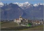 Vor dem Hintergrund der mächtigen Wallier Alpen und dem Schloss von Aigle ist ein ASD Regionalzug bei Aigle auf dem Weg nach Les Diablerets.