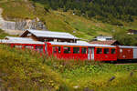 Der vierachsige Personenwagen A 4162, ex BVZ A 2062, ein Mitteleinstiegswagen der ersten Klasse, abgestellt in Realp (Uri) von/bei der DFB Dampfbahn Furka-Bergstrecke AG am 07 September 2021, aufgenommen aus einem fahrenden MGB-Zug heraus.

Der Wagen wurde 1961 von SIG (Schweizerische Industrie-Gesellschaft) in Neuhausen am Rheinfall gebaut und an die damalige BVZ (Brig-Visp-Zermatt-Bahn / BVZ Zermatt-Bahn) als A 2062 geliefert. Nach dem Zusammenschuss am 01. Januar 2003 der BVZ mit der Furka-Oberalp-Bahn (FO) zur Matterhorn-Gotthard-Bahn wurde er zum MGB A 2062, im Jahr 2015 ging er dann an die DFB. Im Mai 2017 war er der erste reine 1. Klasse-Wagen im DFB-Rot.

TECHNISCHE DATEN
Hersteller: SIG
Baujahr: 1961
Spurweite: 1.000 mm (Meterspur)
Anzahl der Achsen 4 (2´2´)
Länge über Puffer : 15.780 mm
Länge des Wagenkastens: 14.900 mm
Breite: 2.656 mm
Höhe: 3.365 mm
Drehzapfenabstand: 11.010 mm
Achsabstand im Drehgestell: 1.800 mm
Laufraddurchmesser: 675 mm
Bremszahnrad: System Abt  (Drehgestell Seite Visp/Talseite)
Eigengewicht:  11,8 t 
Ladegewicht:  3 t
Zul. Höchstgeschwindigkeit: 90 km/h
Anzahl der Fenster (1.400 mm breit): 6 (WC-Seite) bzw. 7
Sitzplätze: 34 und 2 Klappsitze
Stehplätze: 6
Lichte Türbreite: 2 x 610 mm
Toiletten: 1
Heizung: Zugsammelschiene RhB/MGB
Bremsen: automatische Vakuum- und Handbremse
Zulassungen: MGB und RhB

Warum ist aus dem BVZ A 2062 nun der DFB A 4162 geworden?
Dies liegt an dem Nummernsystem der der Bahnwagen der DFB.

Die Wagenbezeichnungen setzen sich aus einem Typenschlüssel bestehend aus Buchstaben und einer Nummer zusammen. Die Typenbezeichnung – z.B. das A aus A 2062 - ist genormt. Wenn ein Wagen von der DFB übernommen wird, wird sie deswegen beibehalten, sofern die Art des Wagens gleich bleibt.
Nachstehend die wichtigsten Typenbezeichnungen:
A 1. Klasse-Wagen
B 2. Klasse-Wagen
C 3. Klasse-Wagen (offene Plattform)
D Gepäckwagen
E Offener Hochbordwagen
F Schüttgutwagen
G Gedeckter Güterwagen
K Flachwagen, Regelbauart
L Flachwagen 2-achsig, Sonderbauart
S Flachwagen 4-achsig, Sonderbauart
X Dienstwagen
Y Dienstwagen, nicht in Zügen einsetzbar
Diesem ersten Buchstaben der Typenbezeichnung können weitere Buchstaben zur Kennzeichnung weiterer Merkmale folgen.

Die Systematik der Nummer der Wagenbezeichnung kann von jeder Bahn selbst gewählt werden. Sie hat im Wesentlichen die Aufgabe, jedem Wagen eine eindeutige Identifikation zuzuweisen.
Für die DFB gilt der nachstehende Nummernschlüssel:
1. Ziffer Achsanzahl
2. Ziffer Wagenbauart, für gilt der nachstehende Schlüssel:
      0     Salonwagen
      1     1. Klasse-Wagen
      2     2. Klasse-Wagen
      3     3. Klasse-Wagen
      4     1. und 2. Klasse-Wagen
      5     1./2. Klasse-Wagen mit Gepäckabteil
      6     Güterwagen
      7     Gepäckwagen
      8     Speise- und Barwagen
      9     Dienstwagen
3. und 4. Ziffer in der Regel die zwei Endziffern (der letzten Wagennummer) vor dem Wechsel zur DFB.

Am Beispiel des A 4162, bedeutet die Wagennummer daher:
A = 1. Klassewagen (Norm)
4 = vierachsiger Wagen
1 = 1. Klasse-Wagen (DFB)
62 = Endziffern der BVZ bzw. zuletzt MGB-Bahn

Die Informationen sind der DFB-Broschüre Rollmaterial der DFB entnommen.
