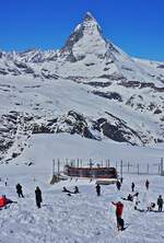 Bei traumhaften Wetter zog es am 10.05.2024 zahlreiche Ausflügler auf den Gornergrat. Im Hintergrund fährt ein Bhe 4/6-Doppel der Gornergratbahn hinunter nach Zermatt.