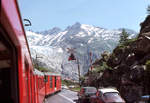 Einfahrt eines FO-Zuges mit Triebwagen 53 in Gletsch, mit schöner Sicht auf den Rhonegletscher.