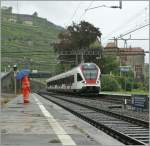 Regen: Pfützen und Schirm zeigen: es regnet, als der SBB Flirt RABe 523 am 16.