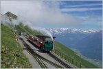 Rauch und Dampf des Brien Rothorn Bahn BRB Dampfzuges vermischt sich auf der Gipfelstation mit den Wolken.