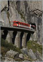 Ein MGB Zug nach Andermatt verlässt den Tunnel bei der Teufelsbrücke in der Schöllenenschlucht und wird in wenigen Minuten sein Ziel erreichen.