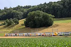Sommerbild: Der BLS MUTZ 515 008 mit Werbung für Postfinance, Kehrsatz Nord.